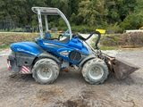 a picture of a blue tractor parked in the dirt