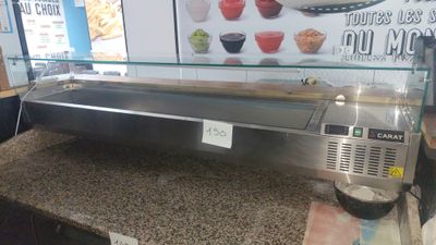 a counter with a glass display case and a bowl of food on it
