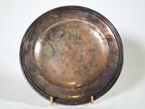 a silver plate on a wooden stand on a white surface