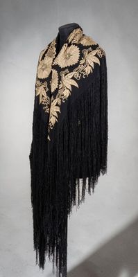 a black and gold shawl with fringes hanging from it