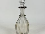 clear glass perfume bottle with a pointed top on a white surface