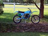 a blue dirt bike parked next to a stone wall