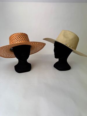deux chapeaux posés sur une tête de mannequin, sur une surface blanche