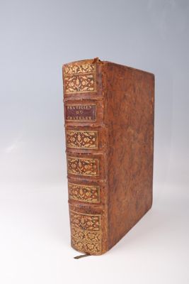 un vieux livre marron avec des bordures dorées posé sur une surface blanche