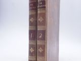 two old books sitting on top of each other on a white surface