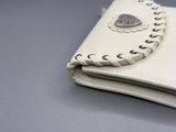 un portefeuille blanc muni d'un bouton, posé sur une table