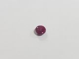 a single ruby stone on a white surface