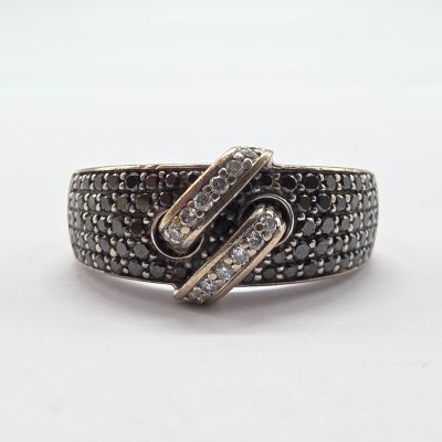 un gros plan d'une bague sertie d'un diamant noir et blanc sur une surface blanche