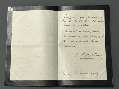 un livre ouvert, sur lequel repose une lettre manuscrite, posé sur une table