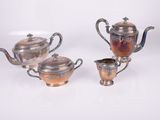 three pieces of silver and copper tea set on a white surface