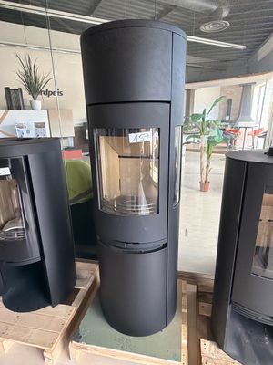 three black wood burning stoves sitting on pallets in a warehouse