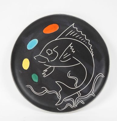 une assiette noire sur laquelle est dessiné un poisson