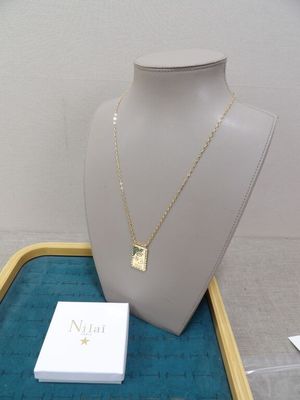 collier en or avec un pendentif carré, présenté sur un mannequin avec une petite carte