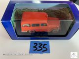 une camionnette orange en plastique se trouve dans une boîte bleue posée sur une table
