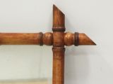 a mirror that has a wooden frame with a wooden arrow on it