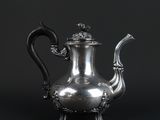 an antique silver teapot with a dragon handle on a black background