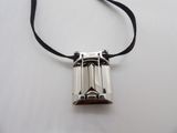 silver plated pendant with a black ribbon on a white surface