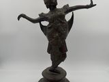 a bronze statue of a woman holding a bird on a pedestal