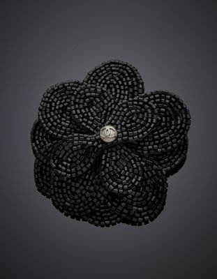 une broche en forme de fleur, composée de perles noires et ornée d'un diamant au centre