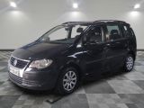 La Volkswagen Touran noire est garée sur un sol en carrelage à damier.