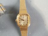 a gold watch sitting on a table next to a silver watch
