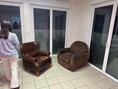 une femme debout dans un salon où se trouvent une chaise et un fauteuil inclinable