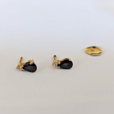 une paire de boucles d'oreilles en or ornées de pierres noires sur un fond blanc