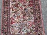 un tapis posé à même le sol, orné d'oiseaux et de fleurs