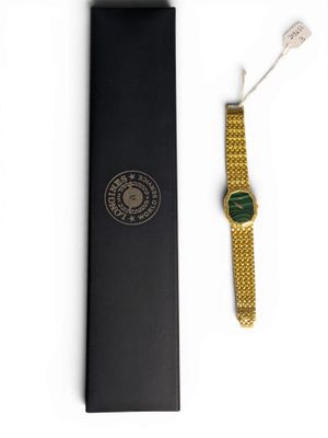 a close up of a watch in a black box on a white surface