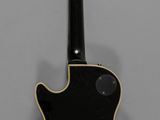 an electric guitar with a black body sitting on a gray surface