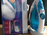 a blue and white steam iron sitting on a table next to a box of clothes