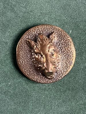 un badge en métal sur lequel est représenté un chien