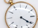 a gold pocket watch with roman numerals on the face
