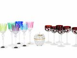 de nombreux verres à vin de différentes couleurs alignés sur une surface blanche