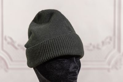 a black mannequin head with a green hat on it