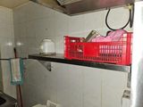 a red basket sitting on a shelf above a toilet