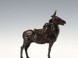 une statue antique en bronze représentant un cheval, posée sur un socle en bois