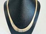 a black mannequin with a gold necklace on it