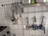 a kitchen with a stove, sink, and pots and pans hanging on the wall
