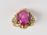 un gros plan d'une bague en pierre rose et diamants posée sur une surface blanche