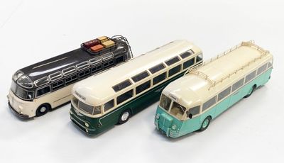 trois bus miniatures posés les uns à côté des autres sur une surface blanche