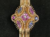 a close up of a gold ring with pink and blue stones