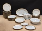 a lot of white and gold plates and bowls on a table
