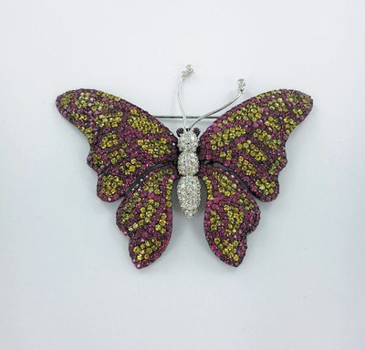 un gros plan d'une broche en forme de papillon posée sur une surface blanche