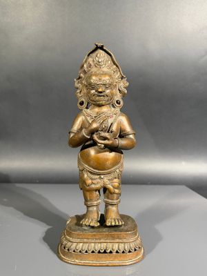 une statue antique en bronze représentant une personne tenant un pot