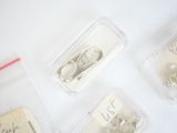 four plastic containers with different types of jewelry in them