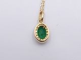 a close up of a gold necklace with a green stone