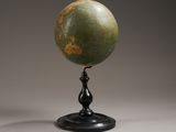 un globe vert posé sur un socle noir