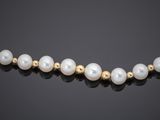 a gold and pearl necklace with pearls on a black background