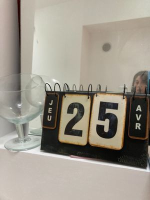 une horloge posée sur une étagère à côté d'un verre à vin et d'un verre à vin